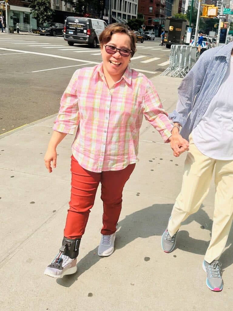 Woman wearing a RehabStride AFO brace walking confidently on a city sidewalk while holding hands